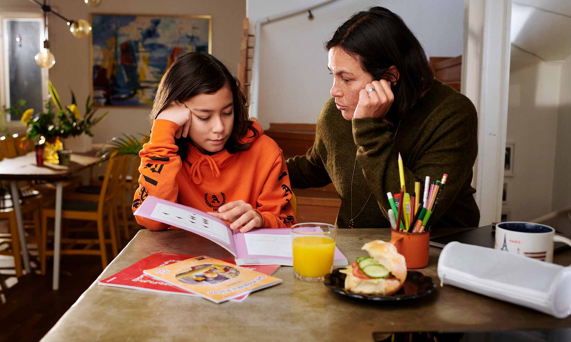 Mamma och barn sitter i köket och läser läxor